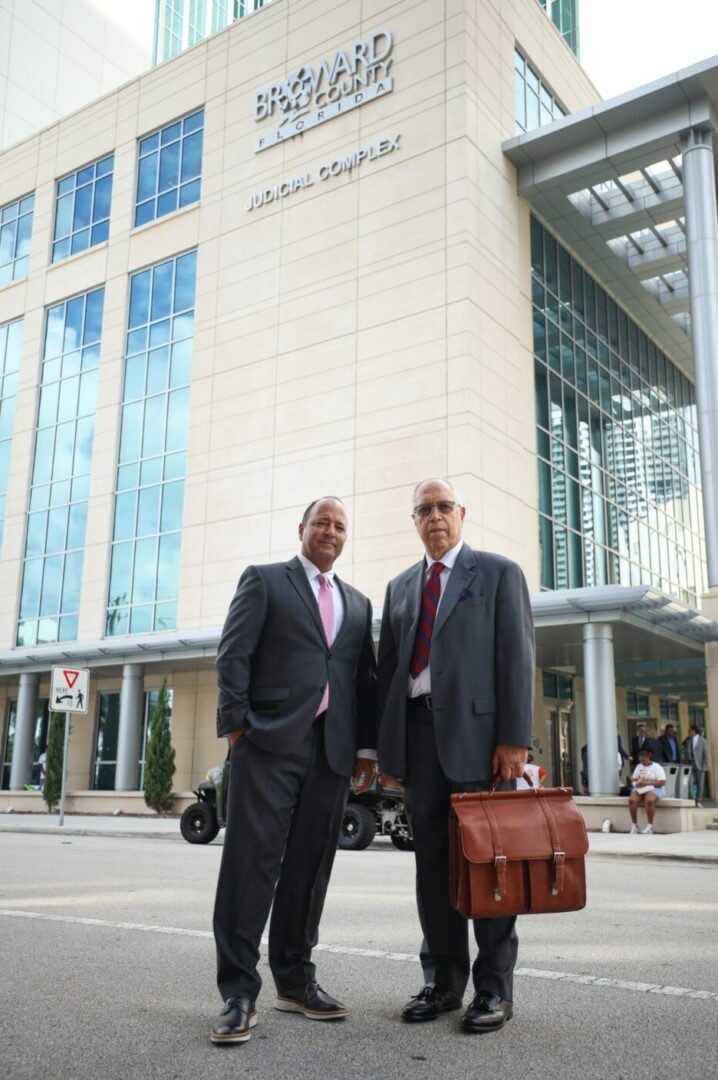 Two attorneys in business suits standing in front of the Broward County Florida Judicial Complex